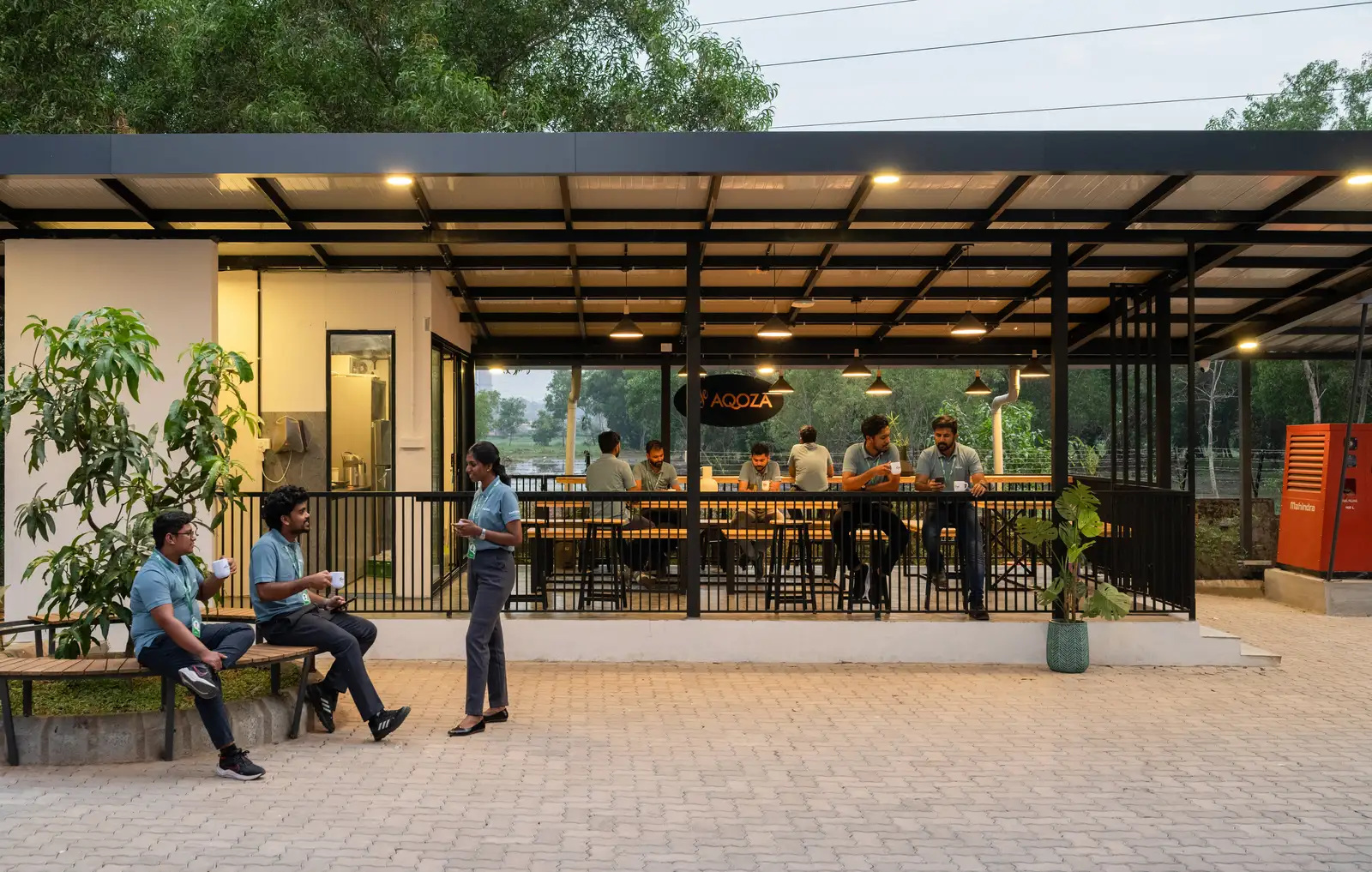 Team members sharing coffee at Cafe AQOZA, the open-air cafeteria at the Kochi campus